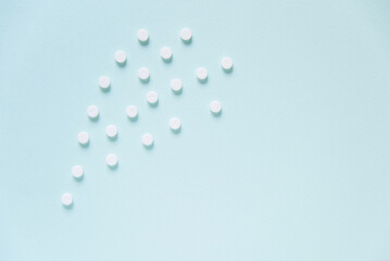 Scattered white pills on blue table. Mock up for special offers as advertising, web background or other ideas. Medical, pharmacy and healthcare concept. Copy space. Empty place for text or logo