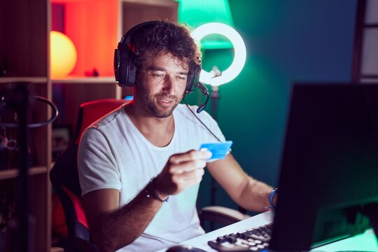 Young hispanic man streamer smiling confident using credit card and computer at music studio