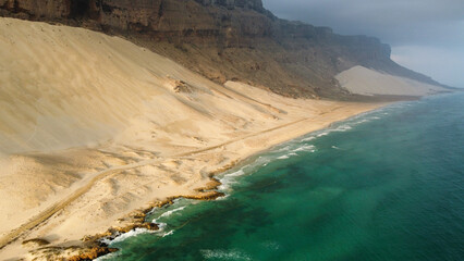 Drone view of blue ocean and sand at golden hour