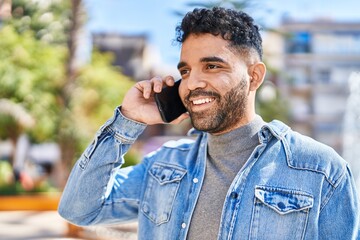 Young hispanic man smiling confident talking on the smartphone at park