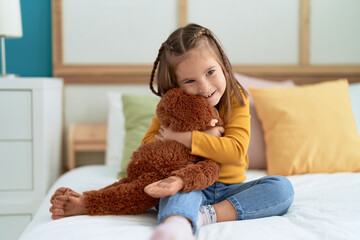 Adorable hispanic girl hugging monkey doll sitting on bed at bedroom © Krakenimages.com