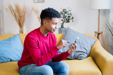 Black man using smartphone on sofa