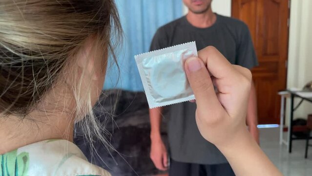 Young asian couple arguing inside bedroom. Wife holding condom with right hand and throw at husband then walk out the room. Marriage problem divorcing and cheating concept