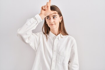 Young caucasian woman standing over isolated background making fun of people with fingers on...