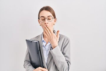 Young caucasian woman wearing business clothes and glasses bored yawning tired covering mouth with hand. restless and sleepiness.