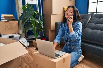 Young chinese woman smiling confident using laptop and talking on the smartphone at home