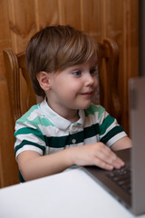 The boy sits at the laptop, the child learns remotely at the computer, classes online