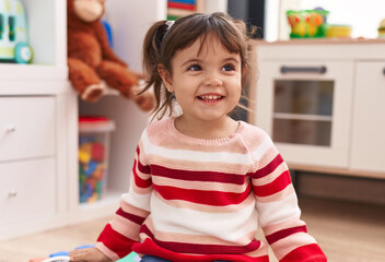 Adorable hispanic girl smiling confident sitting on floor at kindergarten