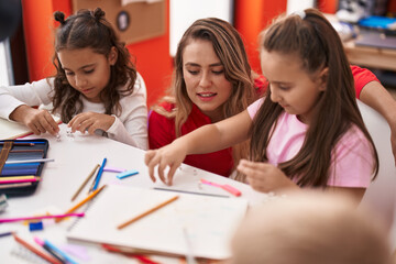 Fototapeta premium Group of kids students and teacher sitting on table drawing on paper at classroom