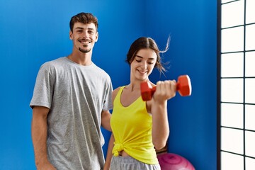 Man and woman couple training using dumbbells at sport center
