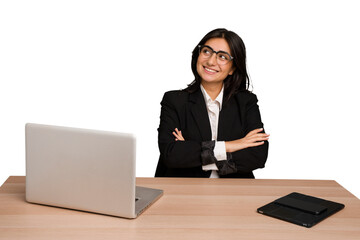 Young indian woman in a table with a laptop and tablet isolated smiling confident with crossed arms.