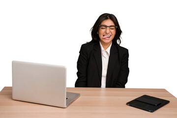 Young indian woman in a table with a laptop and tablet isolated funny and friendly sticking out tongue.