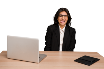 Young indian woman in a table with a laptop and tablet isolated funny and friendly sticking out tongue.