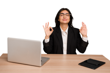 Young indian woman in a table with a laptop and tablet isolated relaxes after hard working day, she is performing yoga.