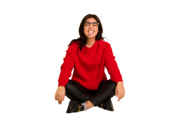 Young indian woman sitting on the floor cut out isolated funny and friendly sticking out tongue.