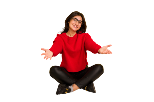 Young indian woman sitting on the floor cut out isolated showing a welcome expression.