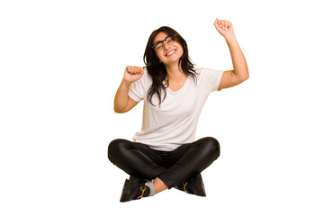 Young indian woman sitting on the floor cut out isolated celebrating a special day, jumps and raise...