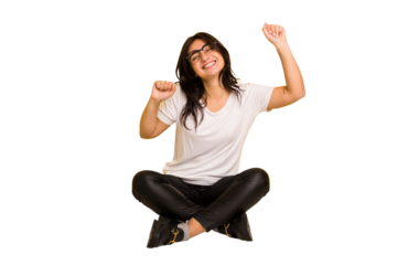 Young indian woman sitting on the floor cut out isolated celebrating a special day, jumps and raise arms with energy.
