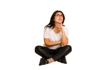 Young indian woman sitting on the floor cut out isolated thinking and looking up, being reflective, contemplating, having a fantasy.