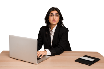 Young indian woman in a table with a laptop and tablet using a mobile phone isolated