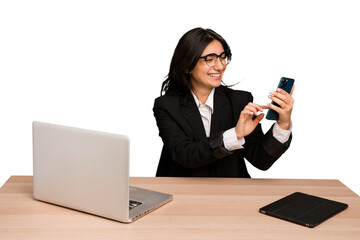 Young indian woman in a table with a laptop and tablet using a mobile phone isolated