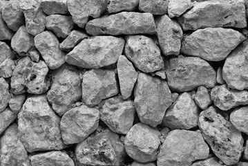 Texture and background of a wall of roughly hewn stones. The image is monochrome in black and white.