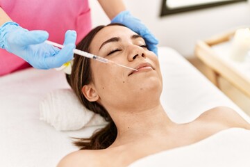 Naklejka premium Young hispanic woman having anti-aging treatment at beauty center.