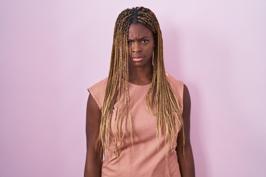 African american woman with braided hair standing over pink background skeptic and nervous, frowning upset because of problem. negative person.