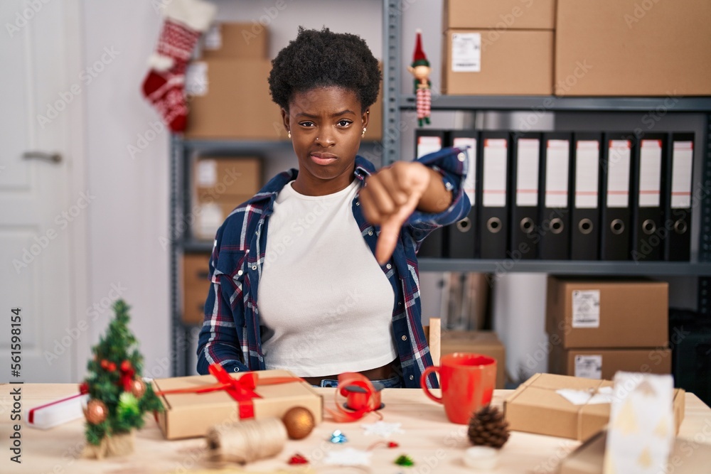 Poster African american woman working at small business doing christmas decoration looking unhappy and angry showing rejection and negative with thumbs down gesture. bad expression.