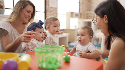 Obraz na płótnie Canvas Teachers and preschool students playing with toys on table at kindergarten