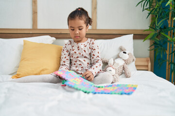 Fototapeta premium Adorable hispanic girl playing maths game sitting on bed at bedroom