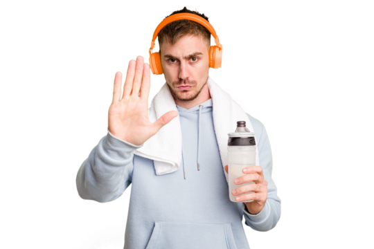 Young caucasian sporty man ready to start his gym day standing with outstretched hand showing stop sign, preventing you.