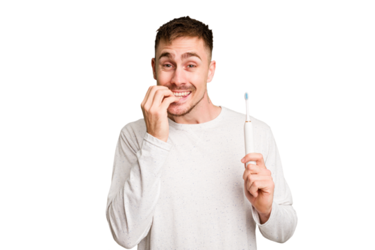 Young caucasian man holding an electric toothbrush isolated cut out biting fingernails, nervous and very anxious.