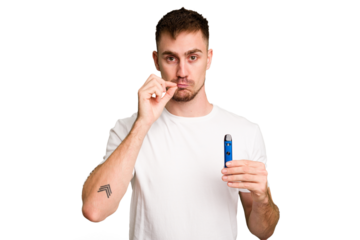 Young caucasian man holding a vaporizer cut out isolated with fingers on lips keeping a secret.