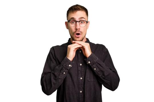 Young caucasian man cut out isolated praying for luck, amazed and opening mouth looking to front.