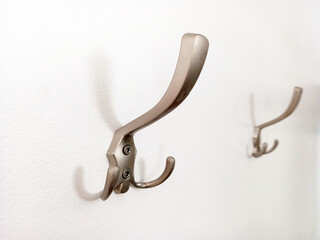 Wall hanger hook isolated on white background. Close up of matt chrome coat rack on white wall. Wall coat rack screwed to the wall.