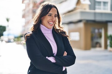 Young hispanic woman smiling confident standing with arms crossed gesture at street