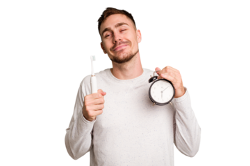 Young man holding an electric brush and an alarm clock cut out isolated