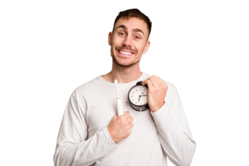 Young man holding an electric brush and an alarm clock cut out isolated