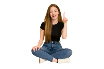 Young redhead woman sitting on the floor cut out isolated showing number one with finger.