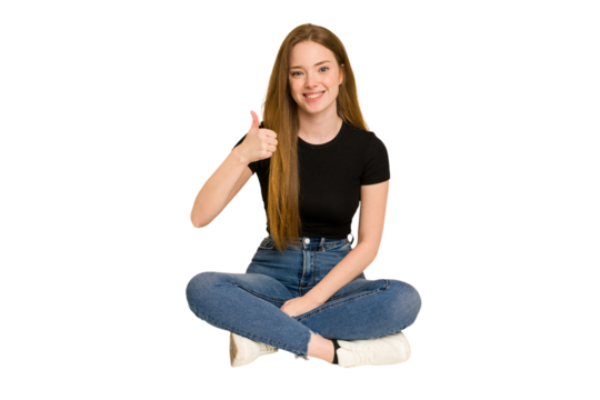 Young redhead woman sitting on the floor cut out isolated smiling and raising thumb up
