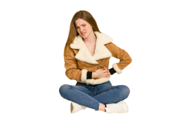Young redhead woman sitting on the floor cut out isolated covering mouth with hands looking worried.