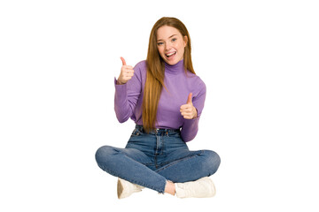 Obraz premium Young redhead woman sitting on the floor cut out isolated showing thumb down and expressing dislike.