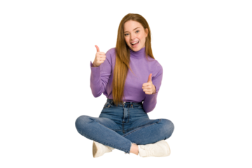 Young redhead woman sitting on the floor cut out isolated showing thumb down and expressing dislike.
