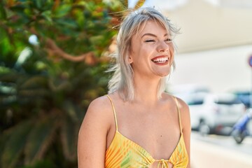 Young blonde woman smiling confident looking to the side at park