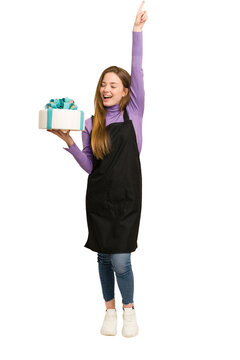 Full body photo of a young redhead woman holding a sweet cake cut out isolated