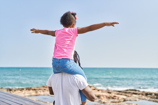 Father And Daughter Holding Girl On Shoulders Standing On Back View At Seaside