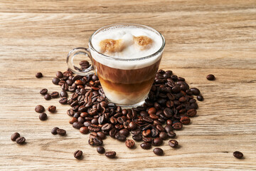  One cup of coffee with milk and coffee beans on wooden surface