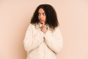 Young african american curly woman isolated praying, showing devotion, religious person looking for divine inspiration.