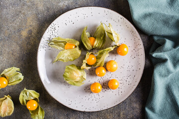 Ripe fruit physalis on a plate. Organic vegetarian food. Top view